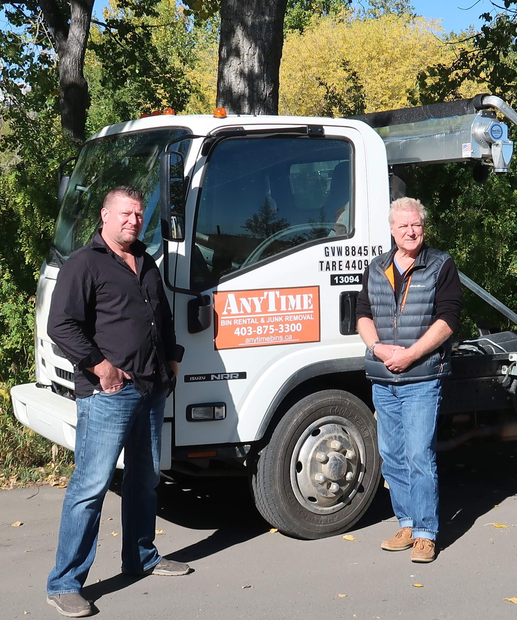 Two men standing beside junk removal truck