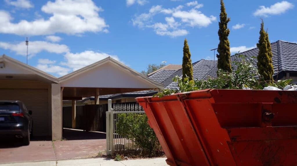 Red dumpster outside suburban house driveway